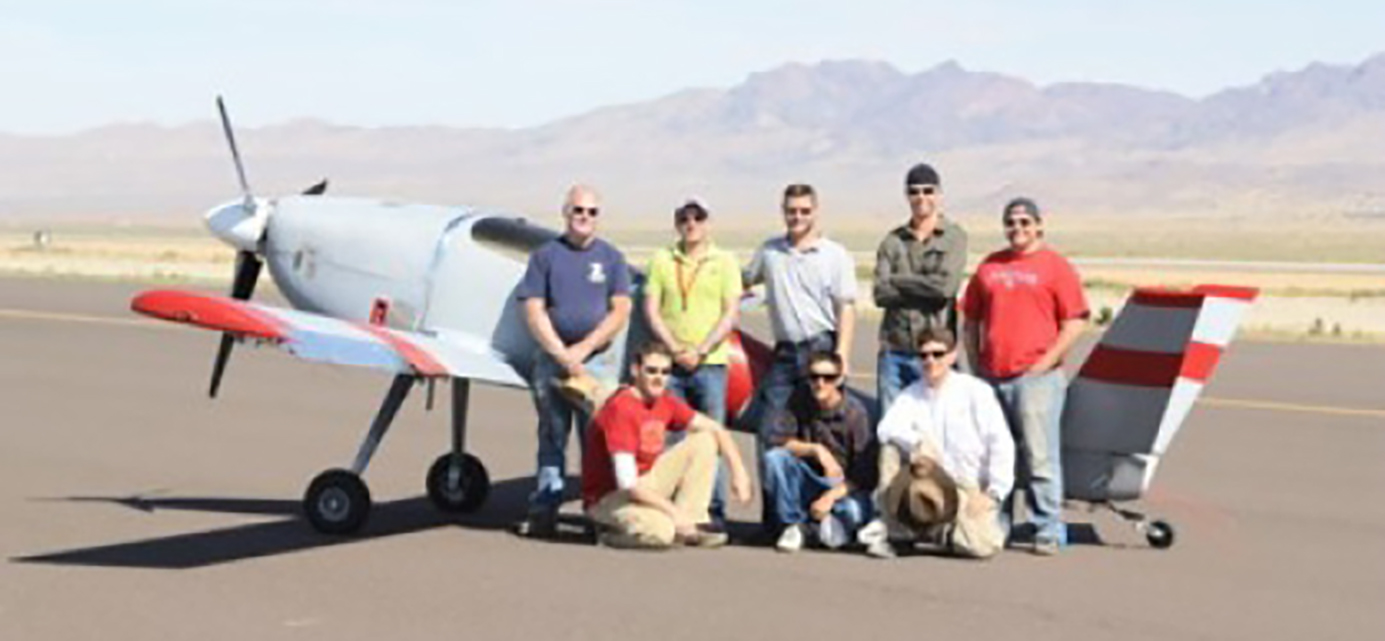 A group of people posing in front of a plane on an airstrip